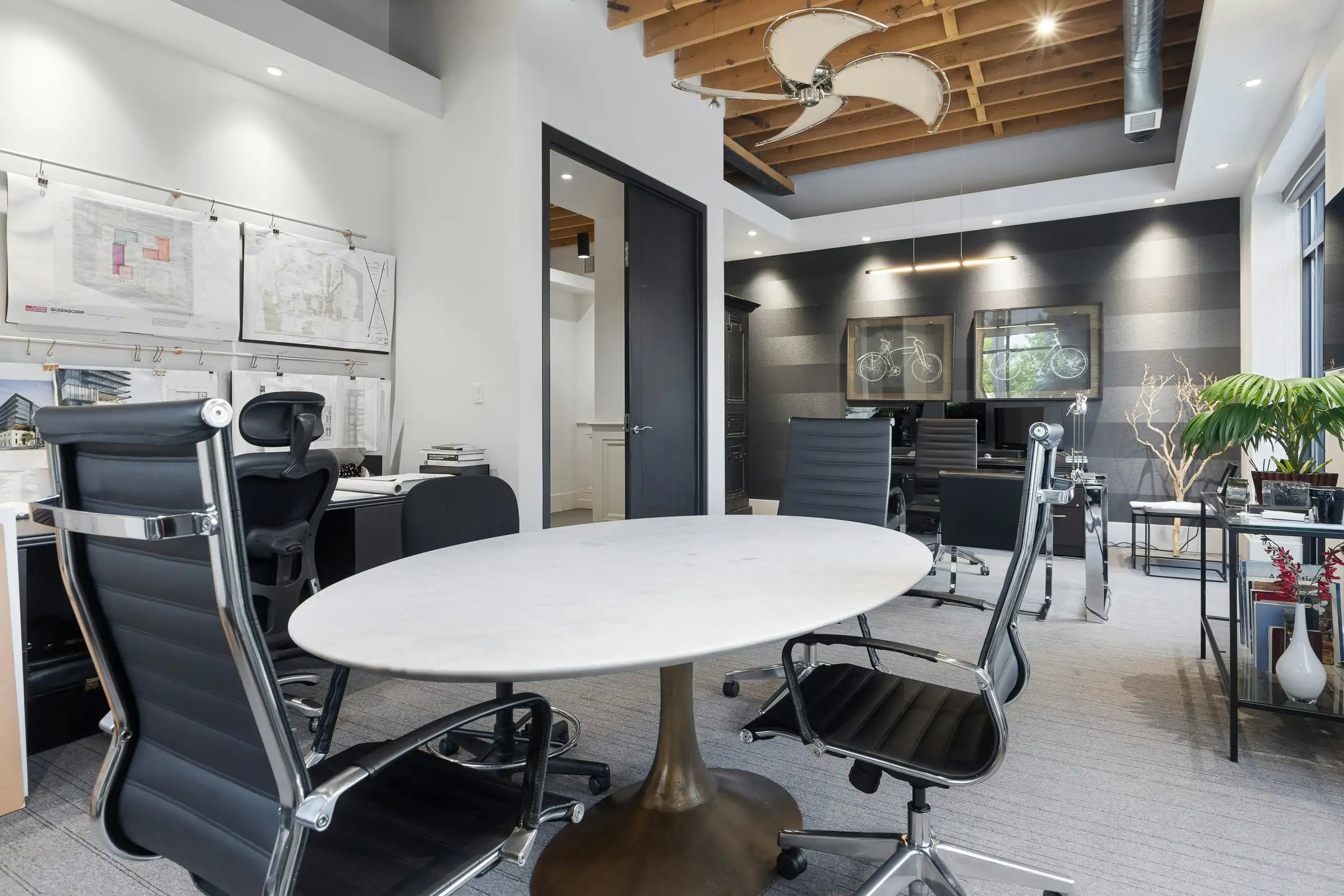 An office with grey feature walls, a round meeting table and glass-walled rooms