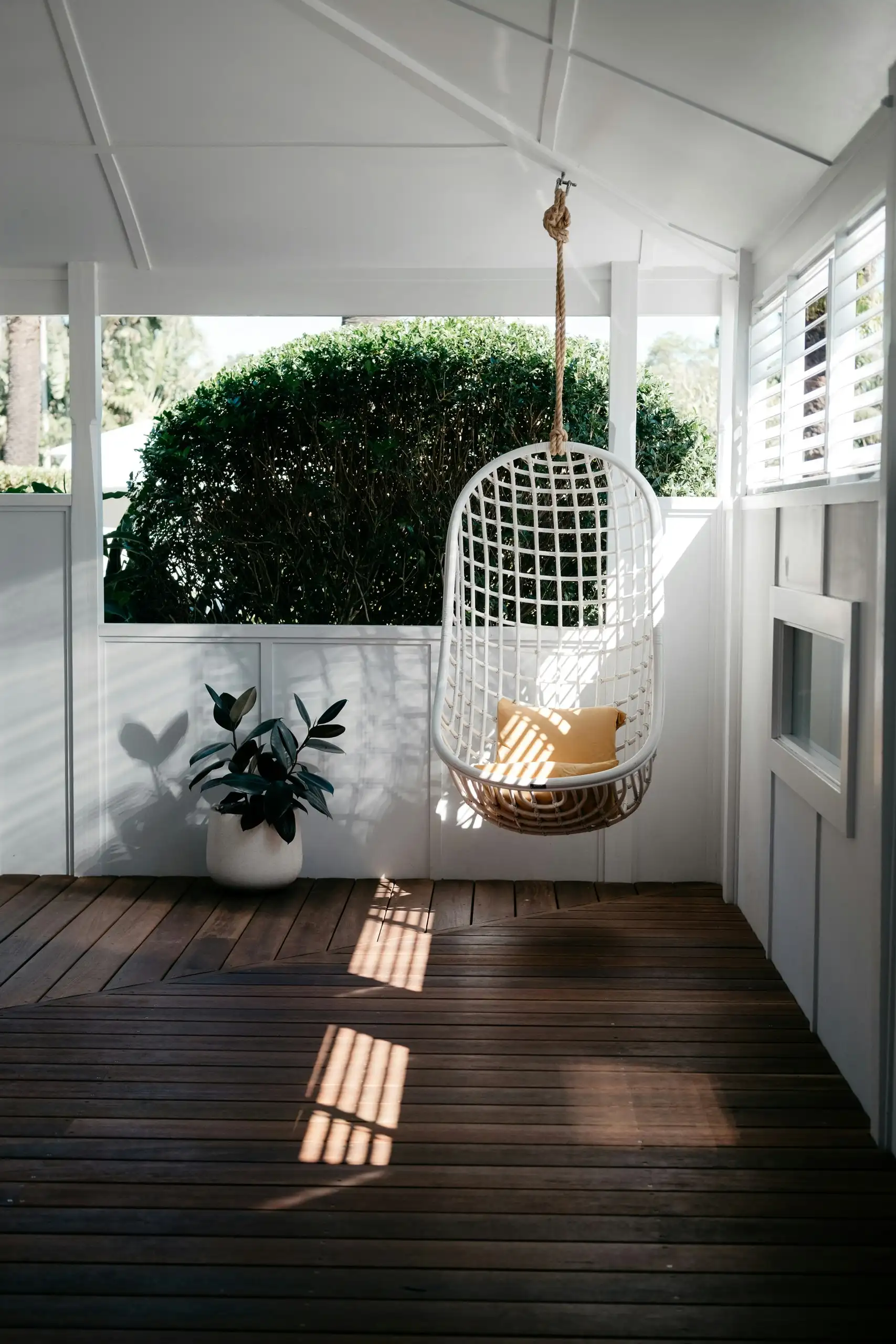 A white painted verandah with a timber floor and a hanging chair