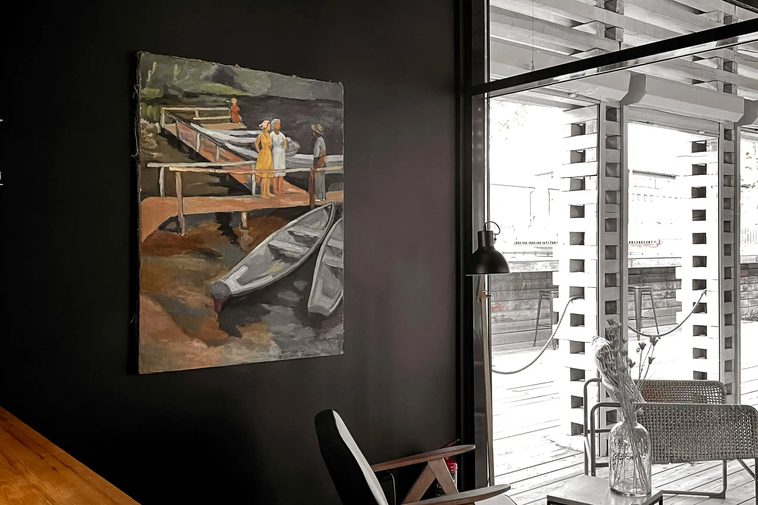 A charcoal wall with a painting of boats at a jetty, white louvres beside it
